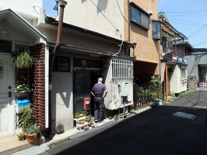 3F建てに挟まれた平屋の外壁