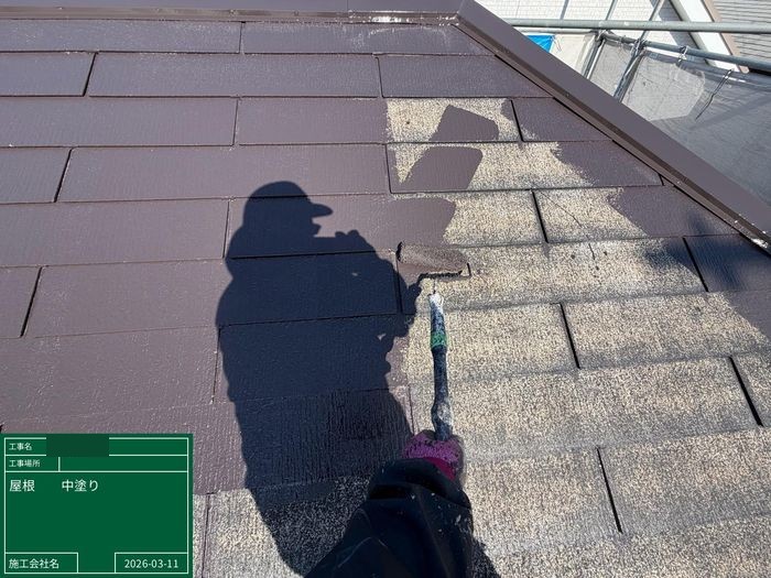 八尾市曙川東のT様邸 スレート屋根塗装の中塗り作業中 職人がローラーでファインパーフェクトベストを塗布している様子