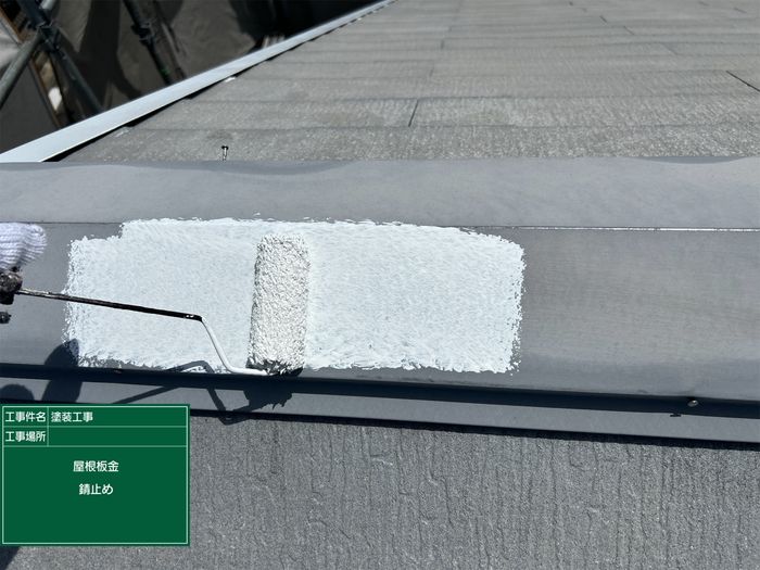 八尾市太子堂のH様邸 棟板金への錆止め塗布 白い錆止め塗料をローラーで塗っている様子